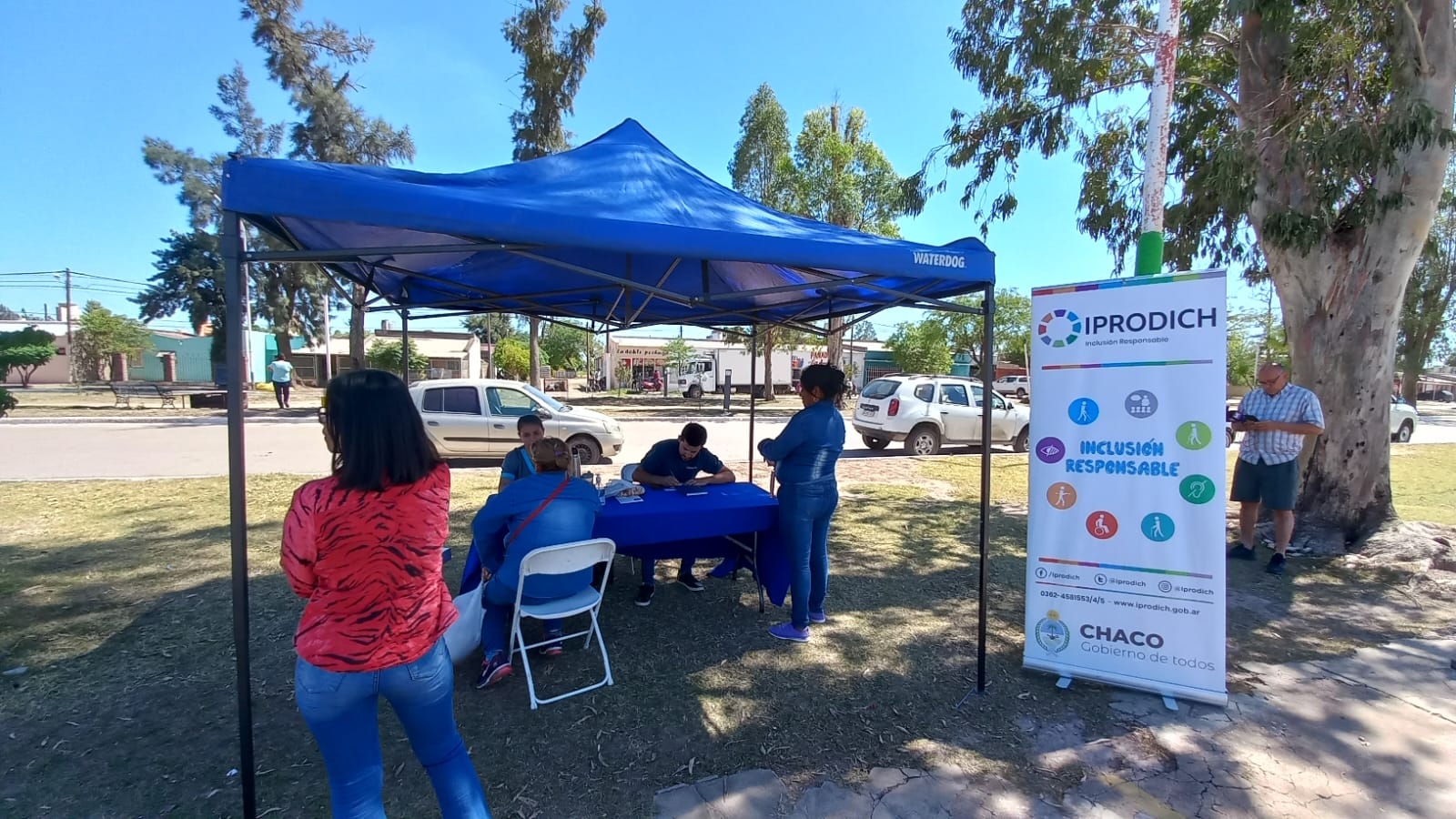 Carpa con gente sentada y parada adentro, hablando entre ellos