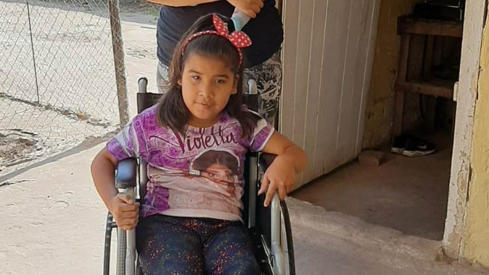Nena sonriendo al recibir su silla de ruedas